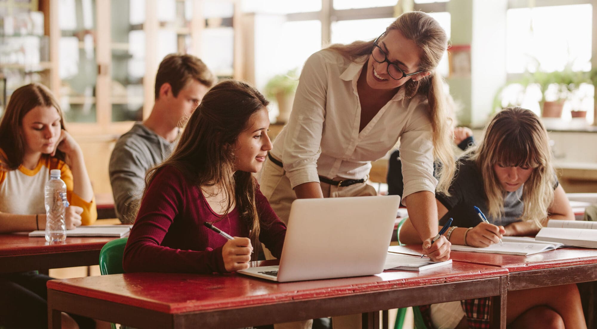 Teacher happy to help student to teacher helping student with behavioural issues in the classroom Teacher happy to help student to teacher helping student with behavioural issues in the classroom