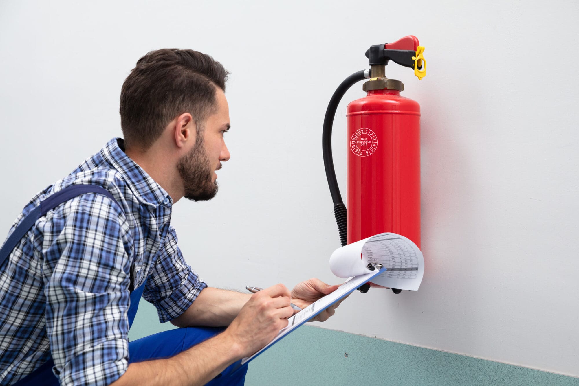 School caretaker checking fire extinguisher in the school School caretaker checking fire extinguisher in the school