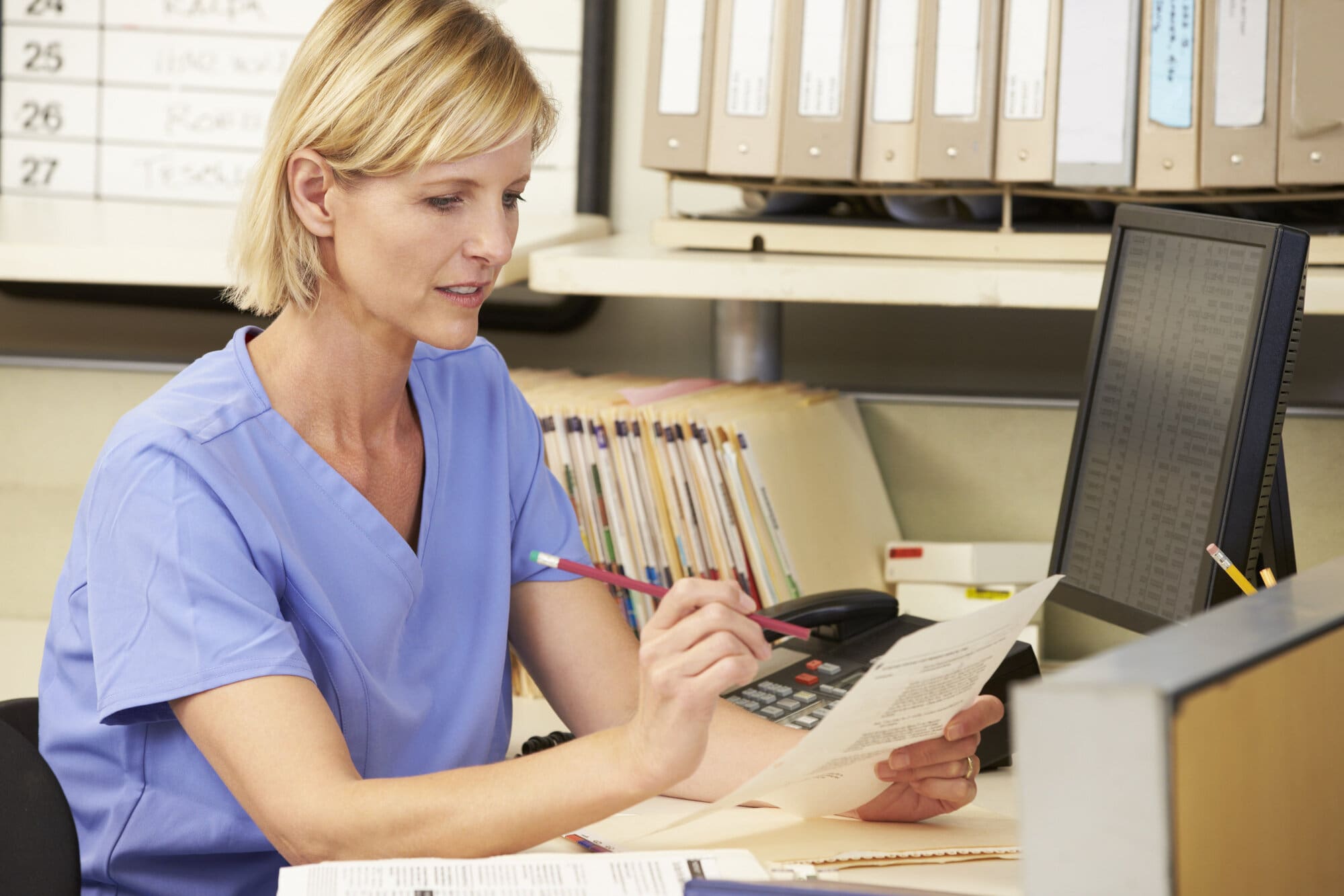 Nurse working in hospital sat at nursing station