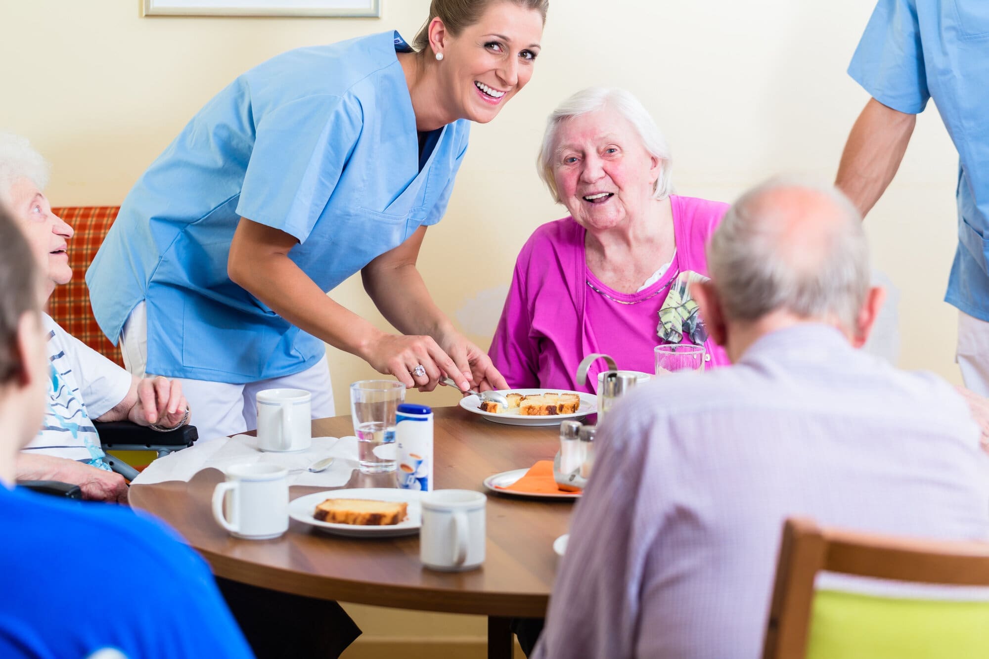 Care home residents eating their meals with assistance