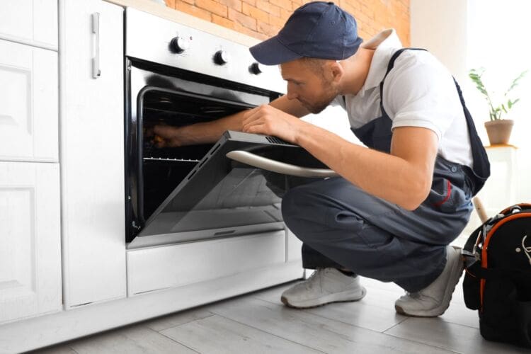 technician repairing electric oven in kitchen